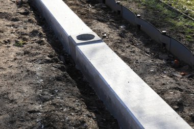 Güneşli öğleden sonra inşaat sırasında toprak yolu çevreleyen beton kaldırım.