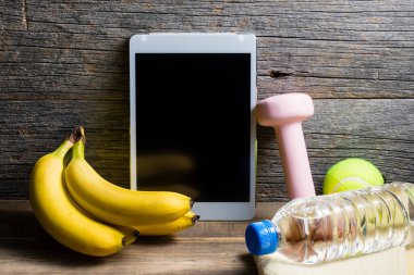 Dambıl, bir şişe su, dijital tablet ve ahşap zemin üzerinde organik yiyecekler. sağlıklı yaşam tarzı kavramı           