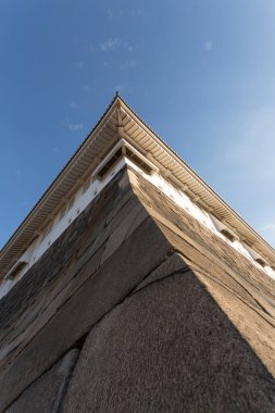 Yukarıya, mavi gökyüzüne karşı eski taş bina köşesine bakıyorum.