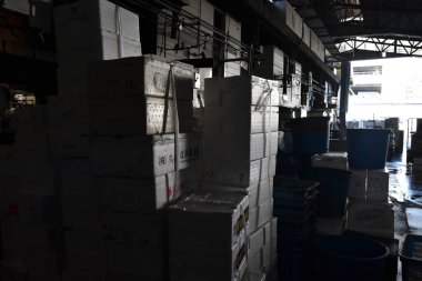 Loş aydınlatılmış sanayi deposunda saklanmış kutular.