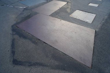 Eski gri asfalt yüzeyinde metal parçalar var.