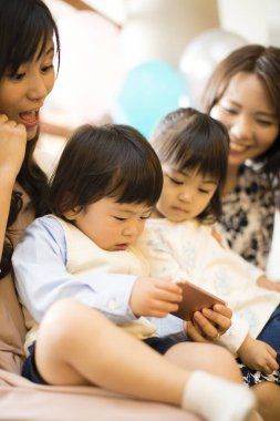 Asyalı anneler ve bebekleri doğum günü partisindeler. 