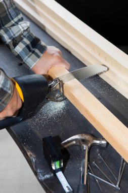 Marangoz tahta testereyle çalışıyor.