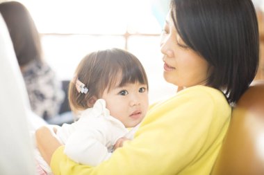 Güzel kızı olan Asyalı bir kadın kucaklıyor. 