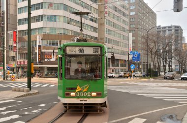 Eski yeşil tramvay Japon şehrinde gündüz hareket ediyor. 
