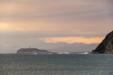 Gün batımında deniz manzarası ve dağlar.