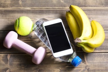 Ahşap arka planda spor ekipmanı, fitness ve spor konsepti olan akıllı telefonun görüntüsü