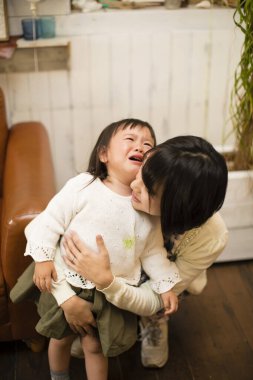 Anne ağlayan bebeğini oturma odasında ağlarken teselli etmeye çalışıyor.