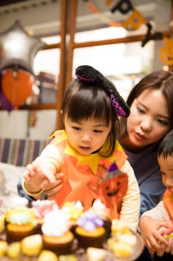 Cadılar Bayramı partisinde çocuklarıyla birlikte Asyalı genç bir anne.