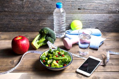 Dambıl, bir şişe su, mezura, akıllı telefon ve organik yiyecekler. sağlıklı yaşam tarzı kavramı           