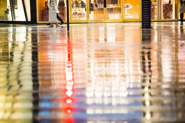 reflection of people walking in wet street of city.