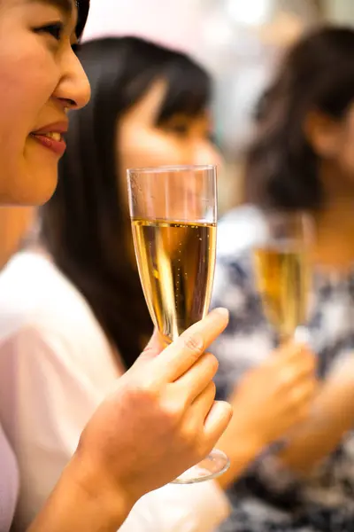 Happy young Asian women drinking champagne at a party
