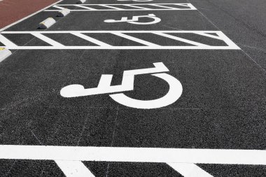 Asfalt yüzeyine beyaz engelli park simgeleri boyanmış