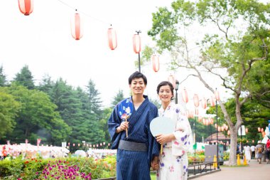 Geleneksel kimono giyen ve parkta Asyalı hayranları olan genç bir Japon çift.