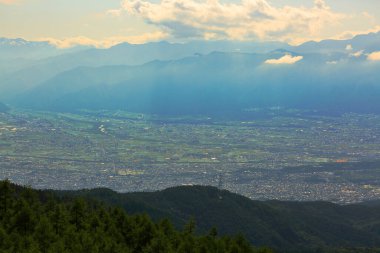Dağlık vadideki kasabanın manzarası ve mavi gökyüzündeki bulutlar.
