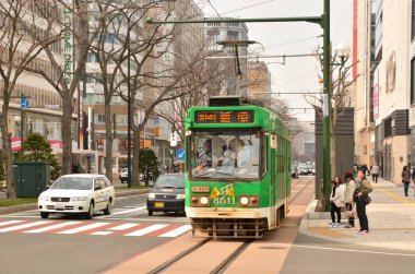Eski yeşil tramvay Japon şehrinde gündüz hareket ediyor. 