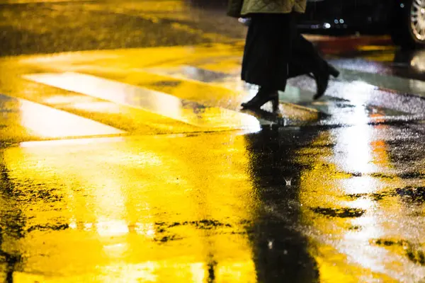 woman crossing road during rainy weather at night