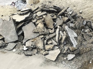 Kırık beton parçaları kumlu zemine saçılmış.