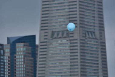 Gökdelenlerin bulanık manzarasına karşı şehirde uçan hava balonu