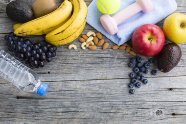 Dambıl, bir şişe su, havlu, top ve ahşap zemin üzerinde organik meyvelerin yakın plan görüntüsü. sağlıklı yaşam tarzı kavramı           