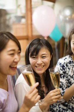Mutlu genç Asyalı kadınlar bir partide şampanya içiyorlar.