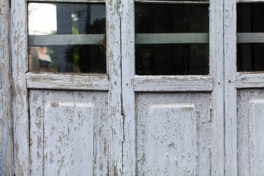 Beyaz çatlamış boya ve camla kaplı eski ahşap kapı.