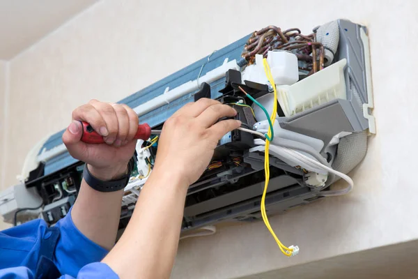 man repairing air conditioning system indoors