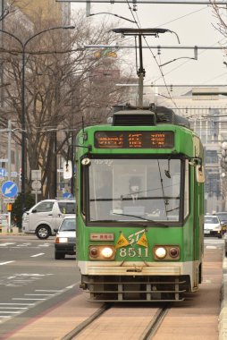 Eski yeşil tramvay Japon şehrinde gündüz hareket ediyor. 
