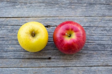 Eski ahşap bir masada sarı ve kırmızı elmalar