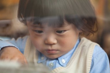 Küçük çocuk camdan aşağı bakıyor.