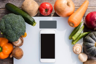 Dijital ölçek ve akıllı telefonu çevreleyen taze sebzeler