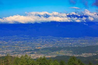 Dağlık vadideki kasabanın manzarası ve mavi gökyüzündeki bulutlar.