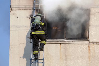 İtfaiyeci endüstriyel binadaki yangını söndürüyor.