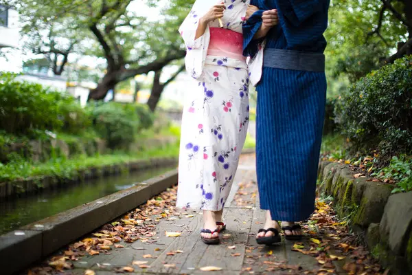 low section of young Japanese couple wearing traditional kimono in summer park