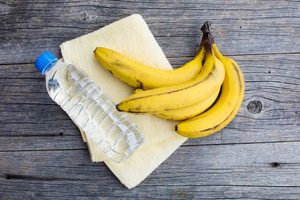 Bananen Handtuch Und Wasserflasche Auf Holzgrund — Stockfoto