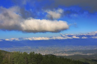 Dağlık vadideki kasabanın manzarası ve mavi gökyüzündeki bulutlar.