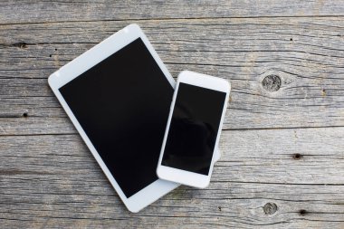 Ahşap masadaki akıllı telefon ve dijital tabletin üst görünümü