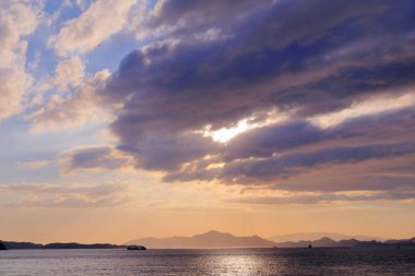 Okyanusun üzerinde güzel bir gün batımı, altın ışık ve bulutlarla romantik deniz manzarası.