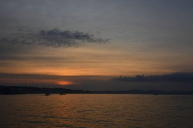 Dağların ve deniz kıyısının üzerinde güzel bir gün batımı             