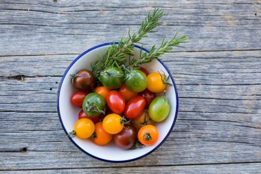 Parlak kiraz domatesleri ve biberiye kasede, üst manzara 