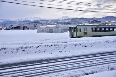Tren istasyonunda tren ve arka planda karlı dağlar