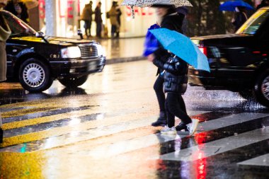 Yağmurlu bir günde sokakta yürüyen insanlar 