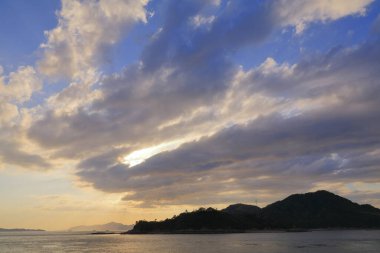 Okyanusun üzerinde güzel bir gün batımı, altın ışık ve bulutlarla romantik deniz manzarası.