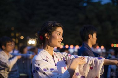 Geleneksel kimono giyen genç Japon çift akşam parkında dans ediyor.