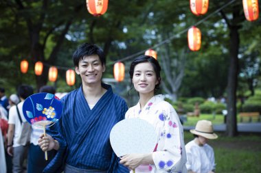 Geleneksel kimono giyen ve parkta Asyalı hayranları olan genç bir Japon çift.