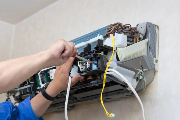 man repairing air conditioning system indoors