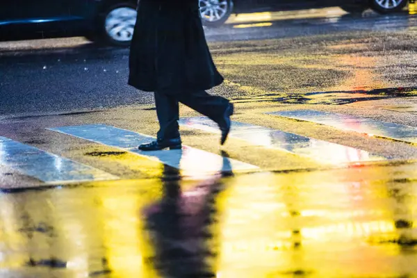 man walking down the street during rainy evening
