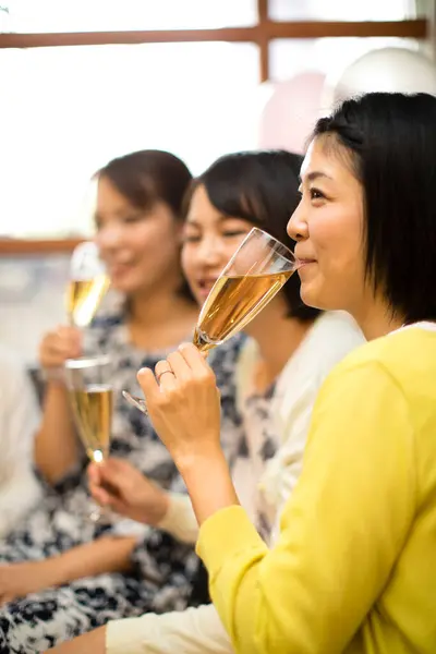 Happy young Asian women drinking champagne at a party