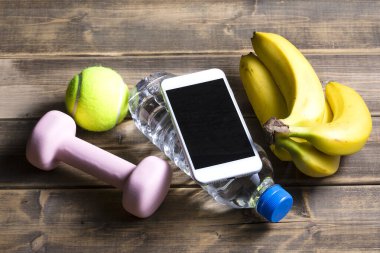 Ahşap arka planda spor ekipmanı, fitness ve spor konsepti olan akıllı telefonun görüntüsü
