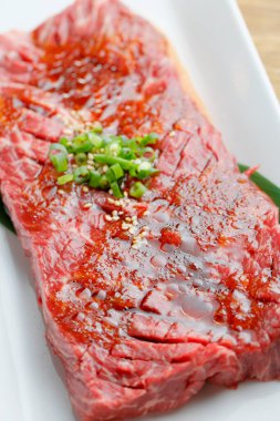 Baharatlı taze çiğ et ve beyaz tabakta soğan.